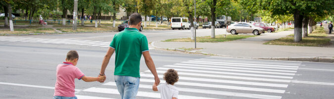 Padre caminando con dos niños en un paso de peatones