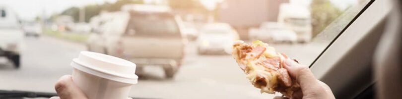 driver with pizza and drink in both hands while driving